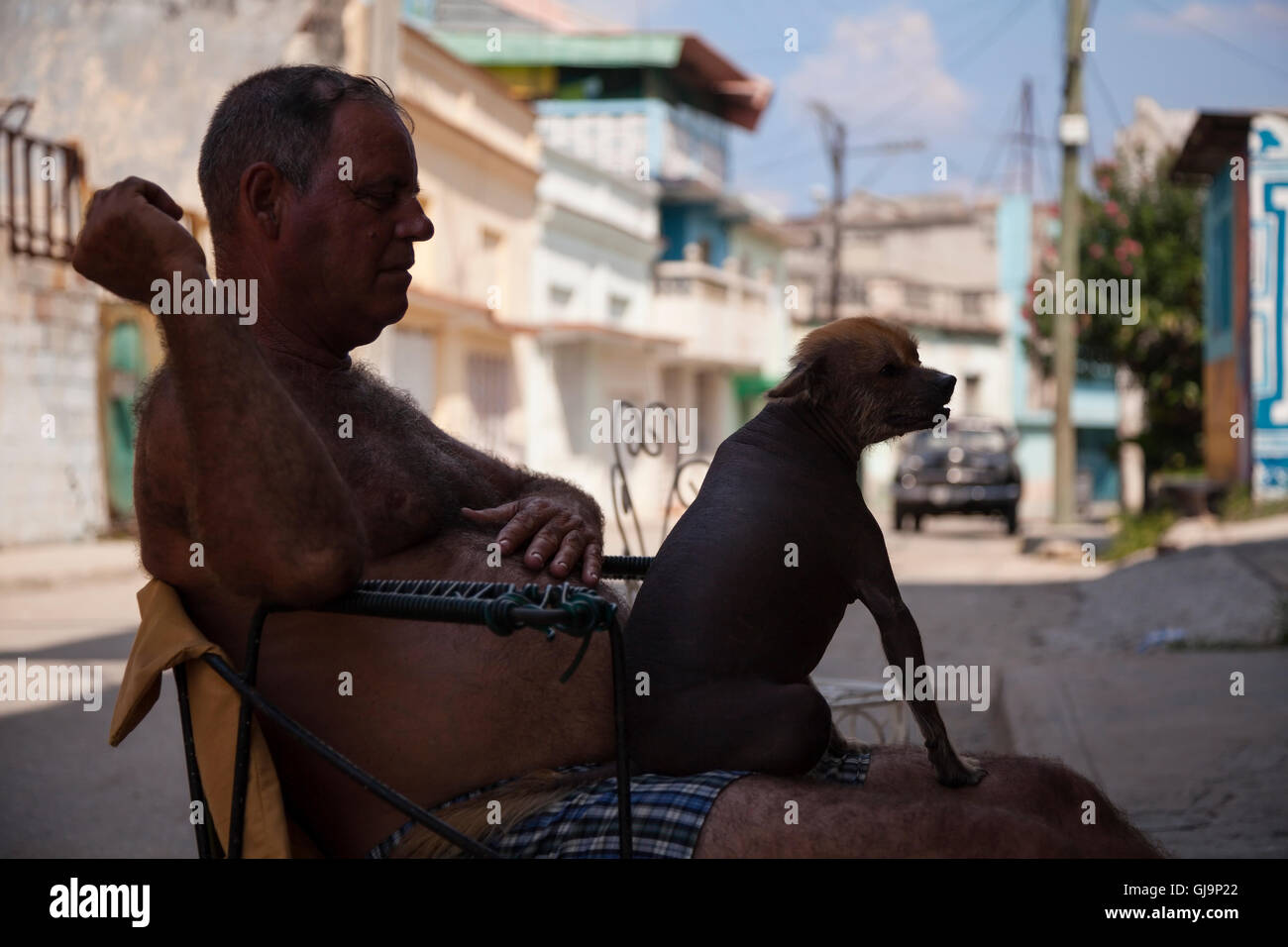 Ein Mann mit seinen haarlosen Hund sitzt auf seinem Schoß in der Gemeinde von Regla, Havanna, Kuba. Stockfoto