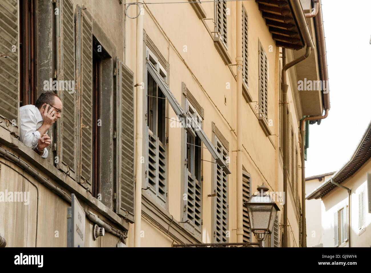 Typische italienische Szene, Mann aus Fenster stützte sich auf Handy, in Florenz, Italien Stockfoto