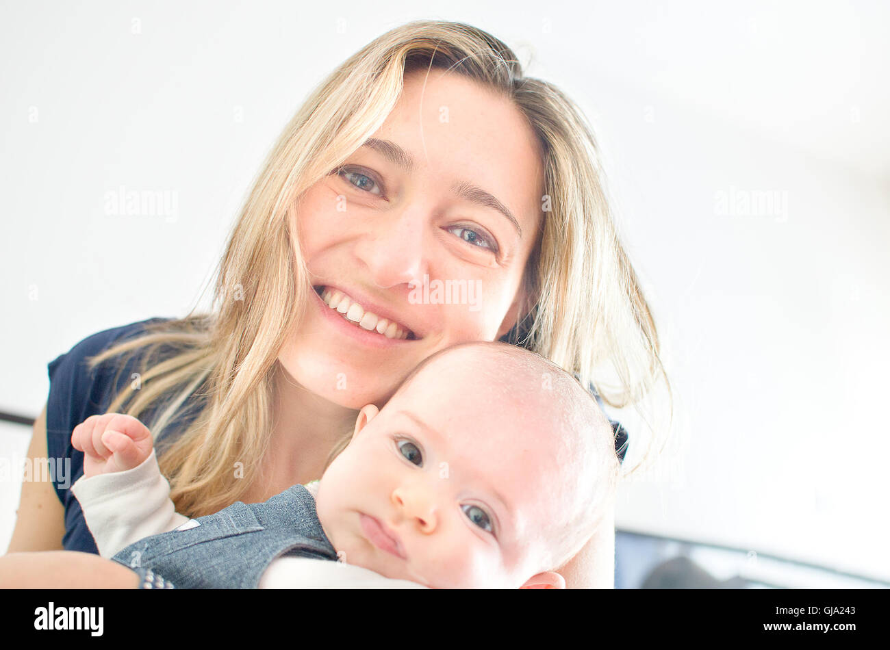 arme Mutter Lächeln Baby - glückliche Frau helles Licht Stockfoto