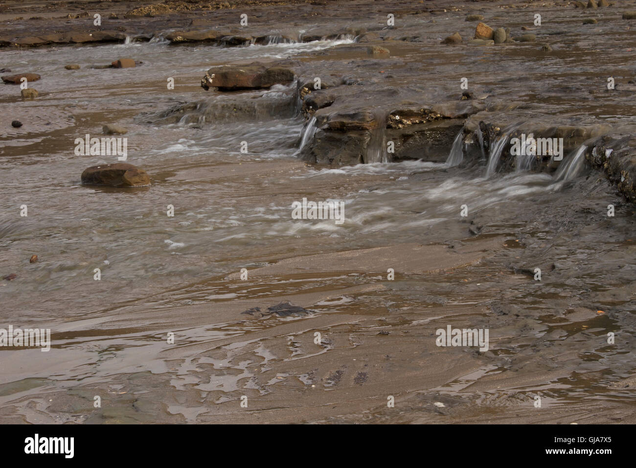 Ebbe-Gezeiten verursacht Mini Wasserfälle entlang des Ufers Stockfoto