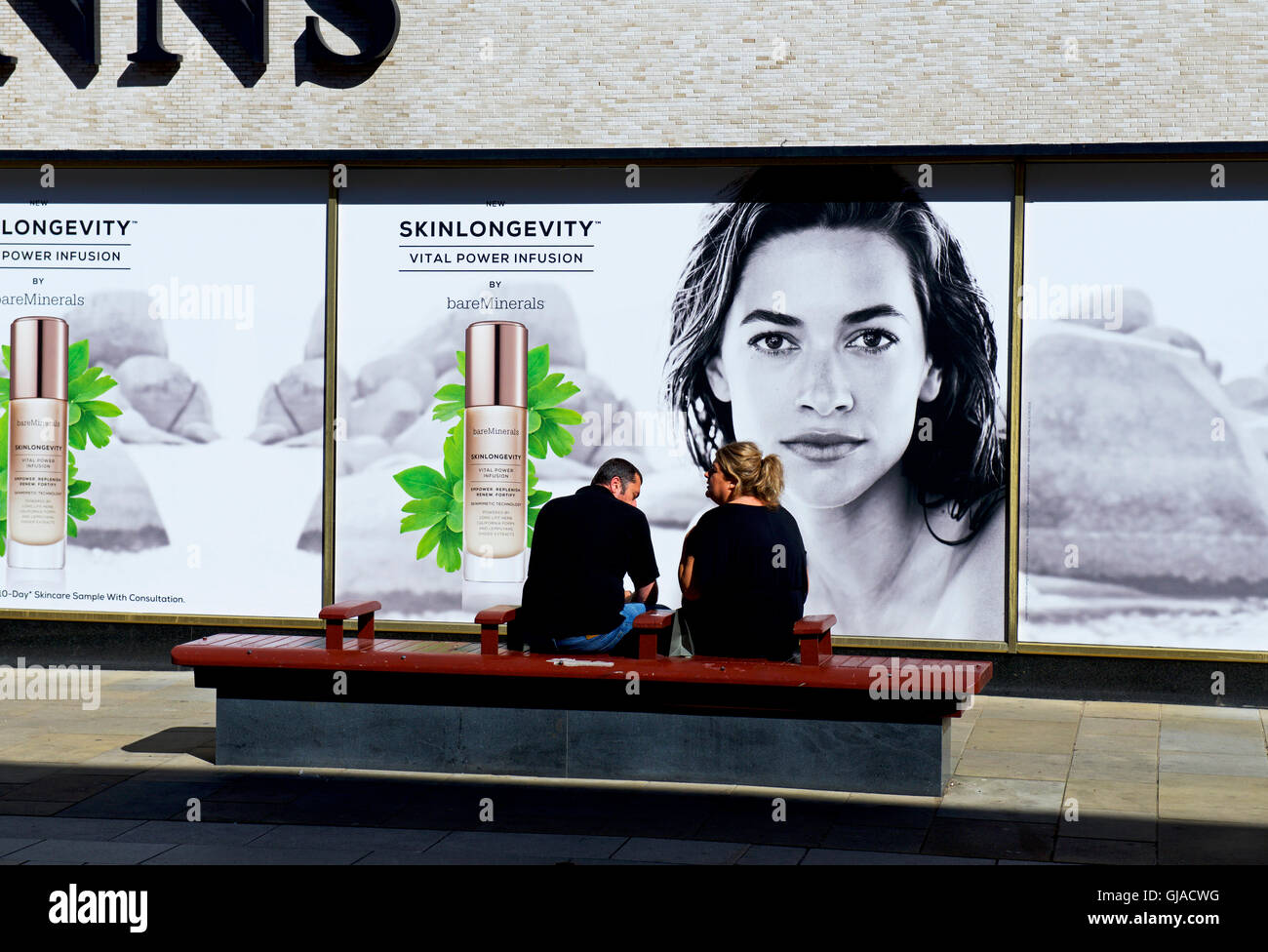 Paar, sitzen vor Werbung, Binns Abteilung speichern, Darlington, County Durham, England UK Stockfoto