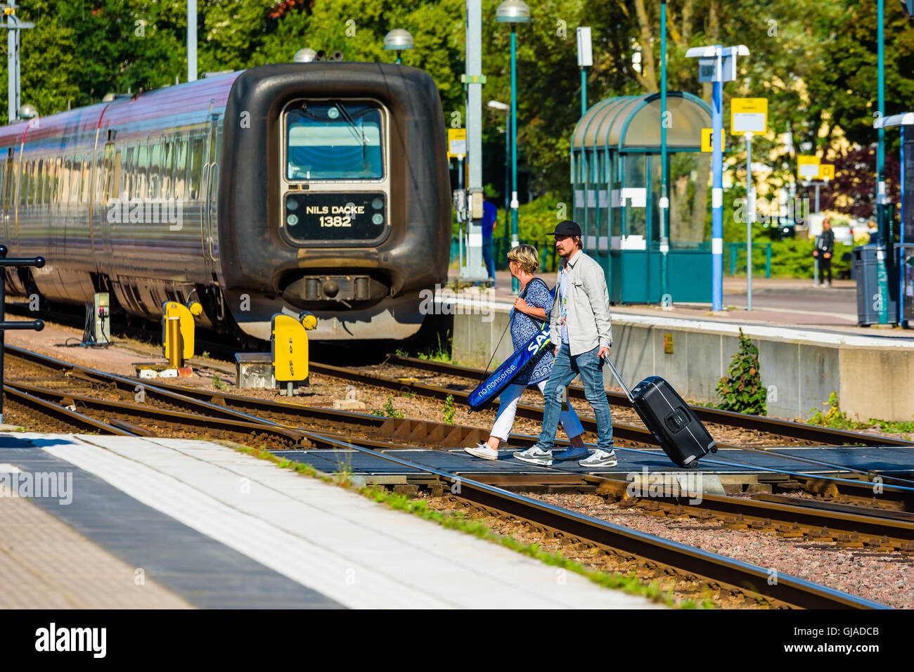 Kalmar, Schweden - 10. August 2016: Menschen mit Trolley-Taschen über die Gleise am Bahnhof kommt man zu der Plattform. Stockfoto