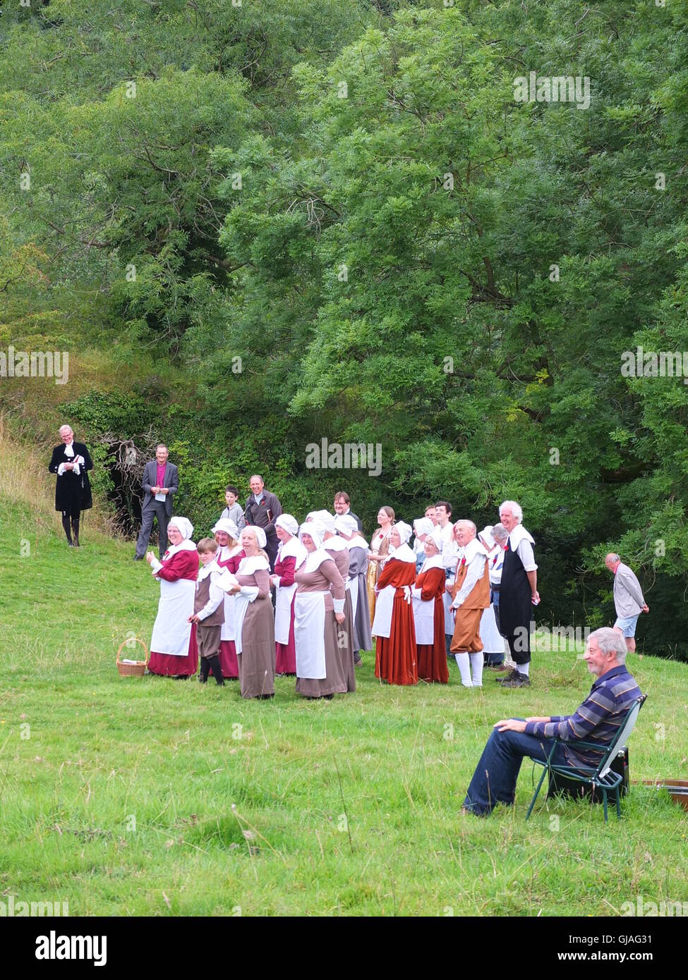 Dorfbewohner in Tracht, der Bischof von Derby und Gitarrist beim Eyam Pest Gedenken Service im Cucklet Delf Stockfoto
