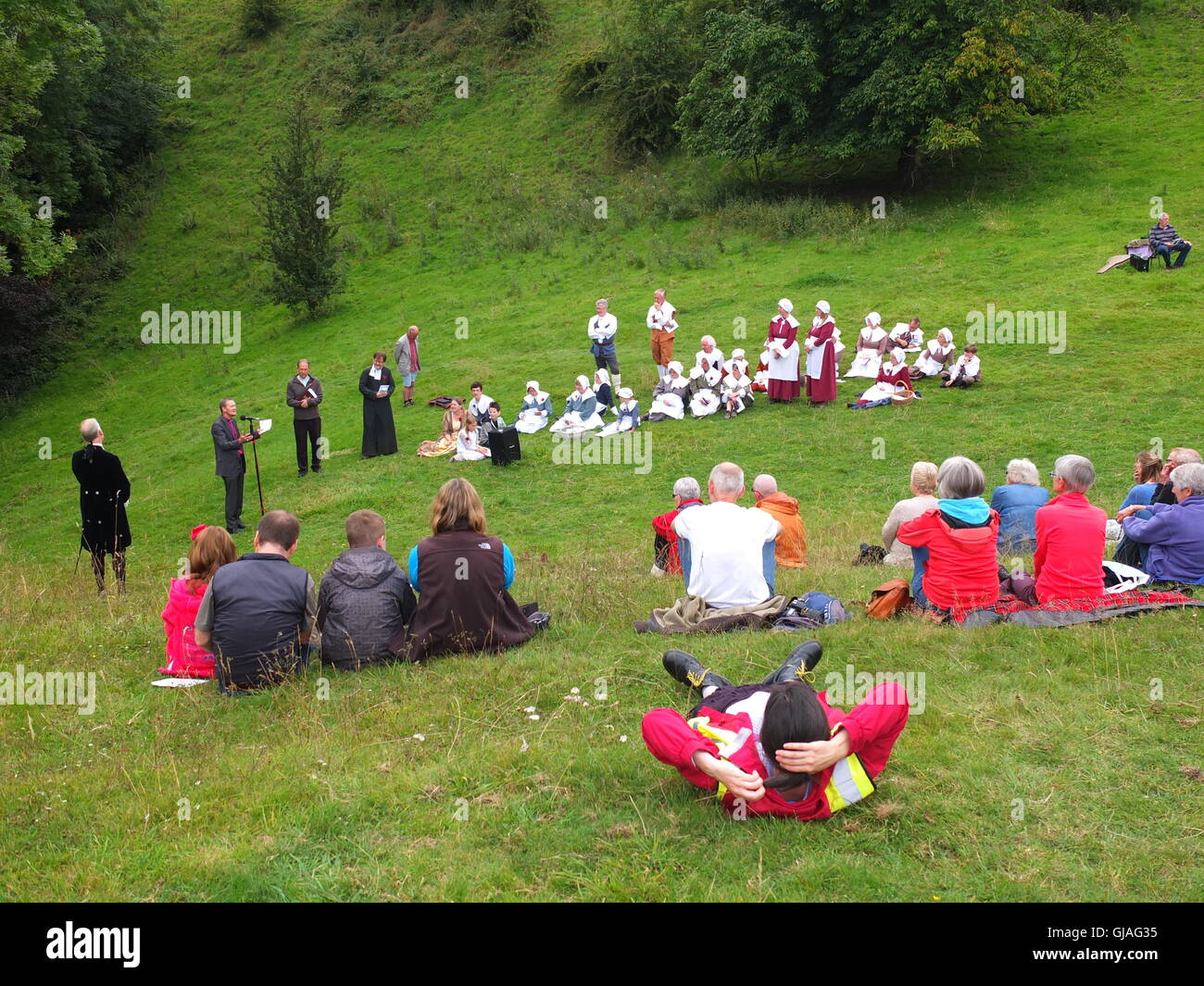 Dorfbewohner in Kostümen führen Eyam Pest Gedenken Service Cucklet Delf als Teilnehmer sehen von den Hügeln Stockfoto