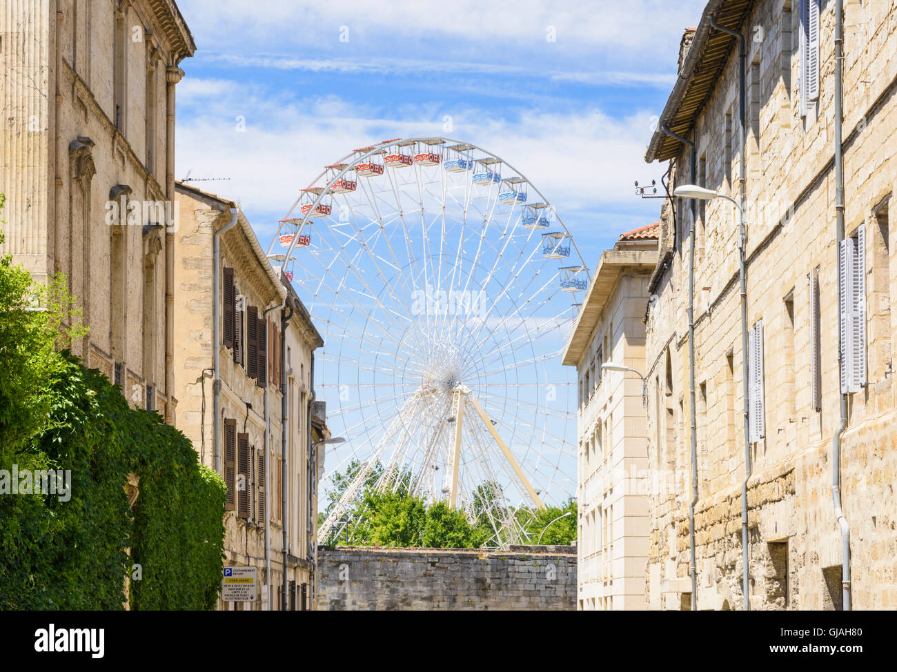 Sommer-Riesenrad gesehen durch eine malerische Straße in der Altstadt, umgeben von der mittelalterlichen Stadtmauer, Avignon, Frankreich Stockfoto
