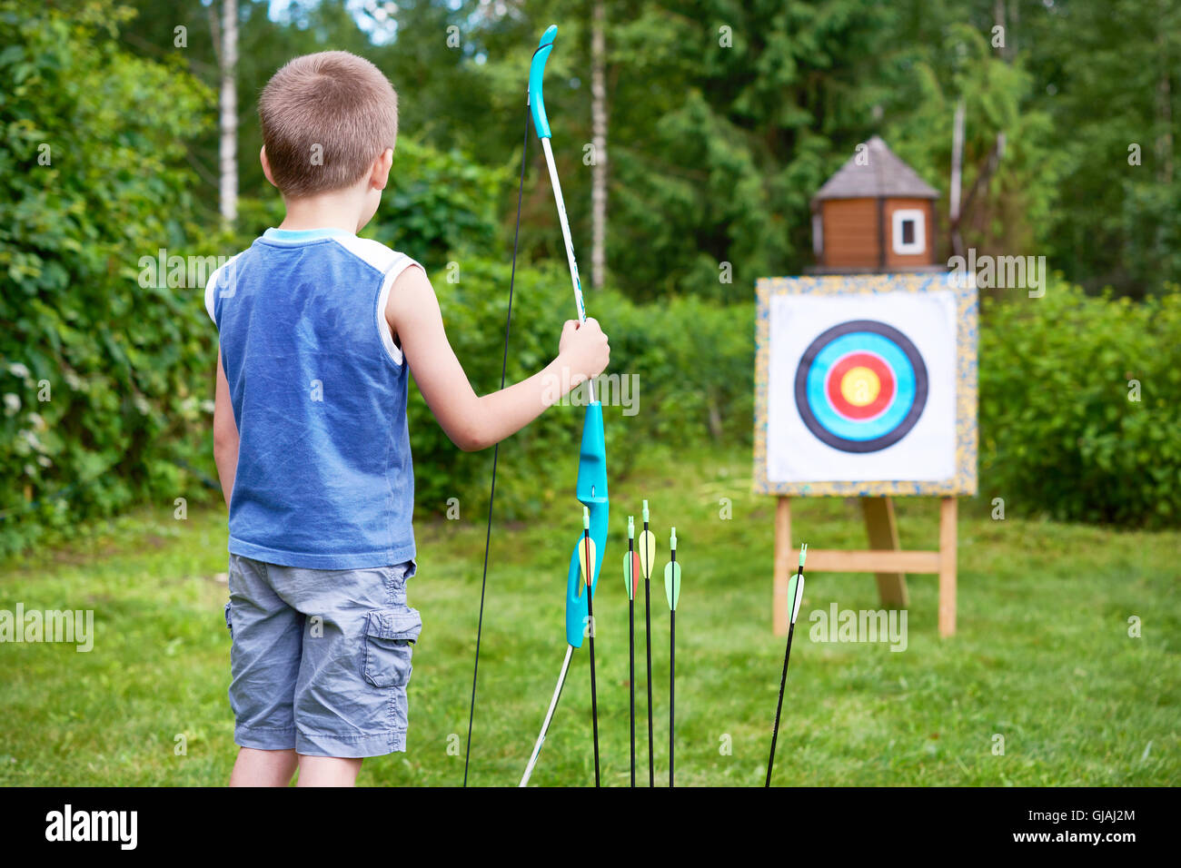 Kleiner Junge mit großen Bogen in der Nähe von Sport Ziel am sonnigen Sommertag Stockfoto