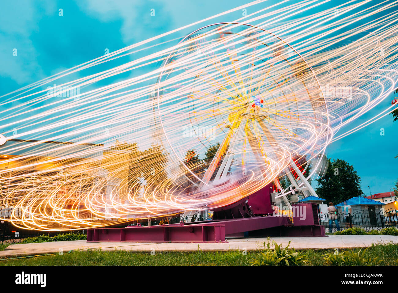 Bewegung verwischt Effekt rund um High-Speed beleuchtete Attraktion Feature In City Vergnügungspark drehen. Riesenrad auf Summe Stockfoto