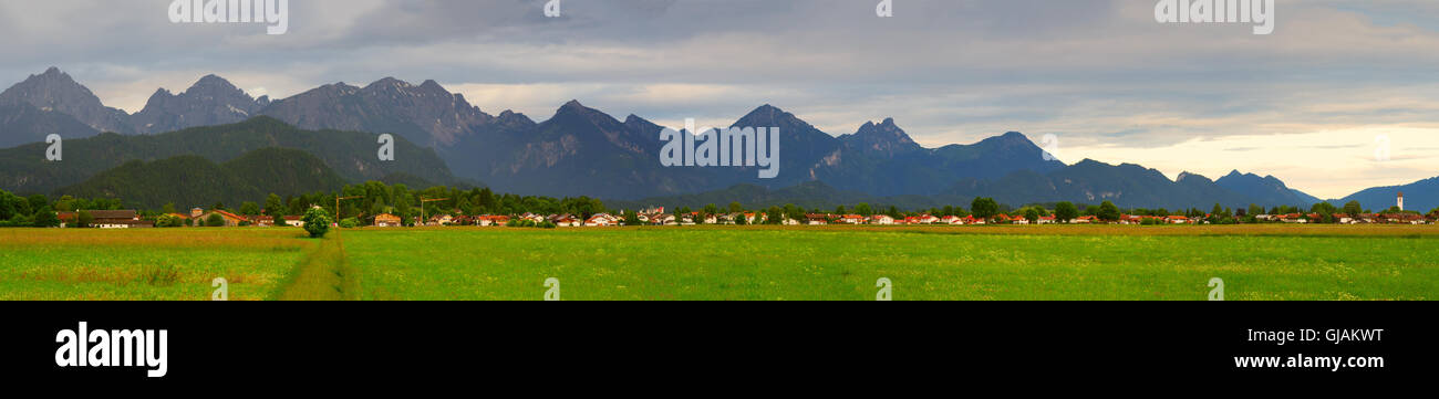 Green Valley in den deutschen Alpen mit einer Kette der Berge am Horizont. Wiese und Feld in Bayern Stockfoto