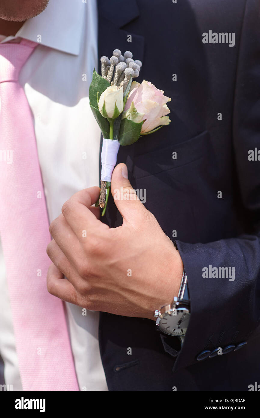 Bräutigam trägt Boutonniere Rosen auf seine Jacke vor der Trauung Stockfoto