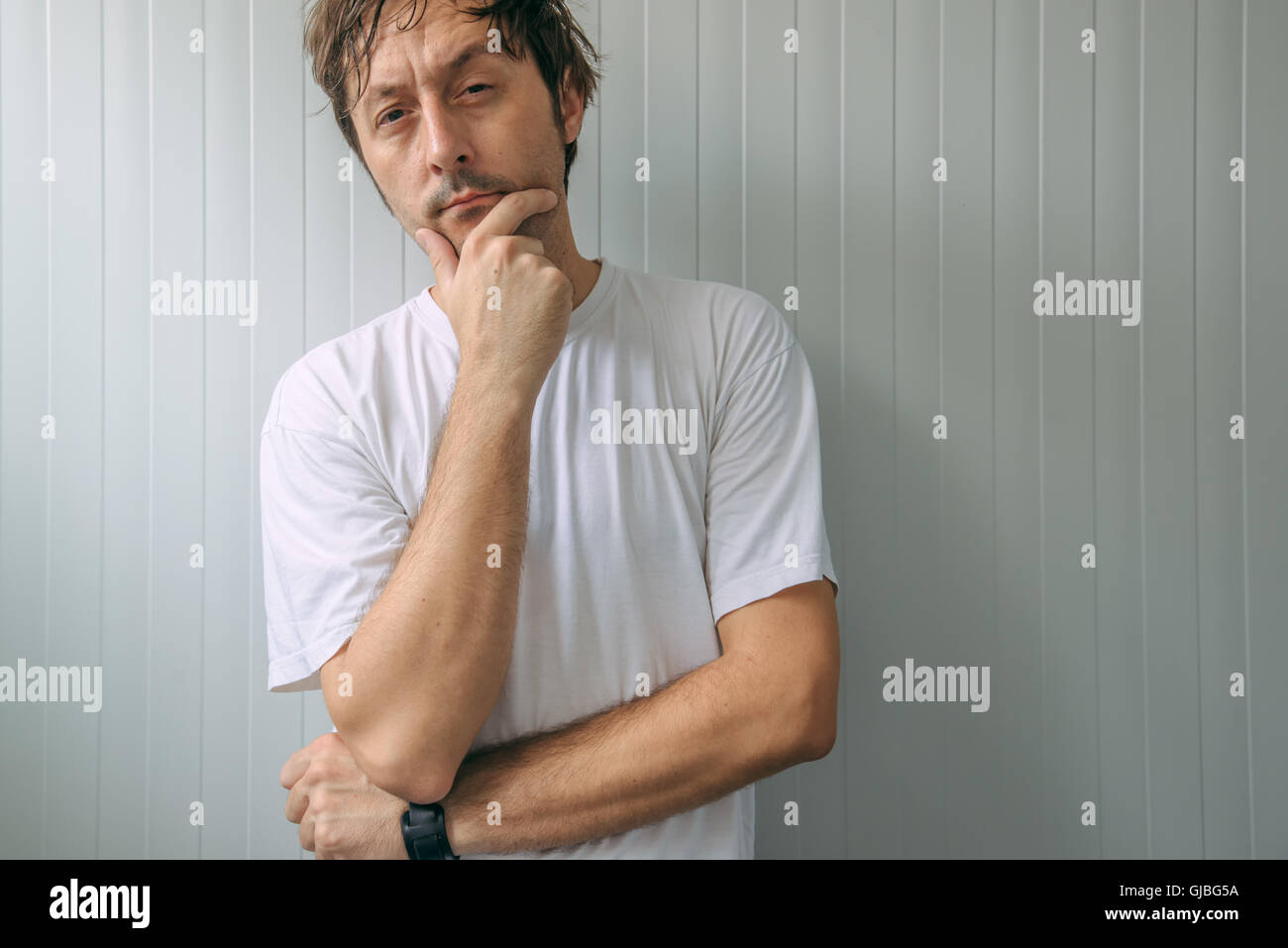 Mann mit missbilligenden Blick in Augen und angehobene Augenbraue Blick in die Kamera mit der Hand am Kinn Stockfoto