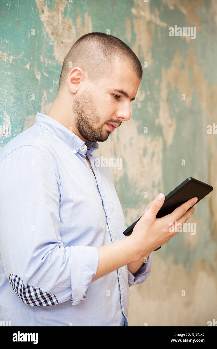 Junger Mann mit einem Tablet von alten Grunge-Mauer Stockfoto