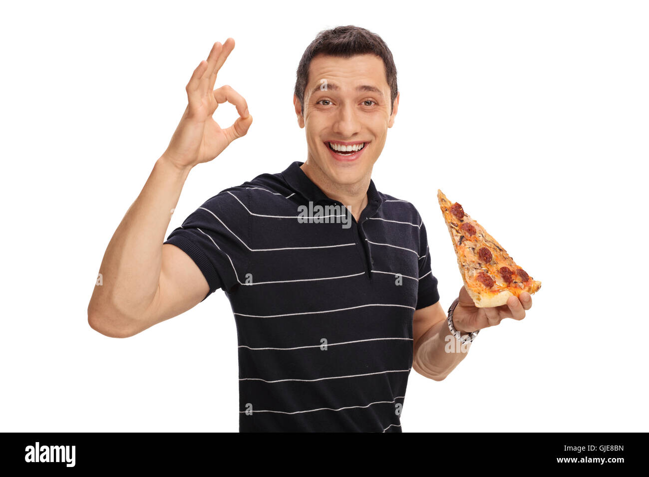 Fröhlichen jungen Mann ein Stück Pizza in einer Hand halten und eine Ordnung Geste mit seiner anderen isoliert auf weißem Hintergrund Stockfoto