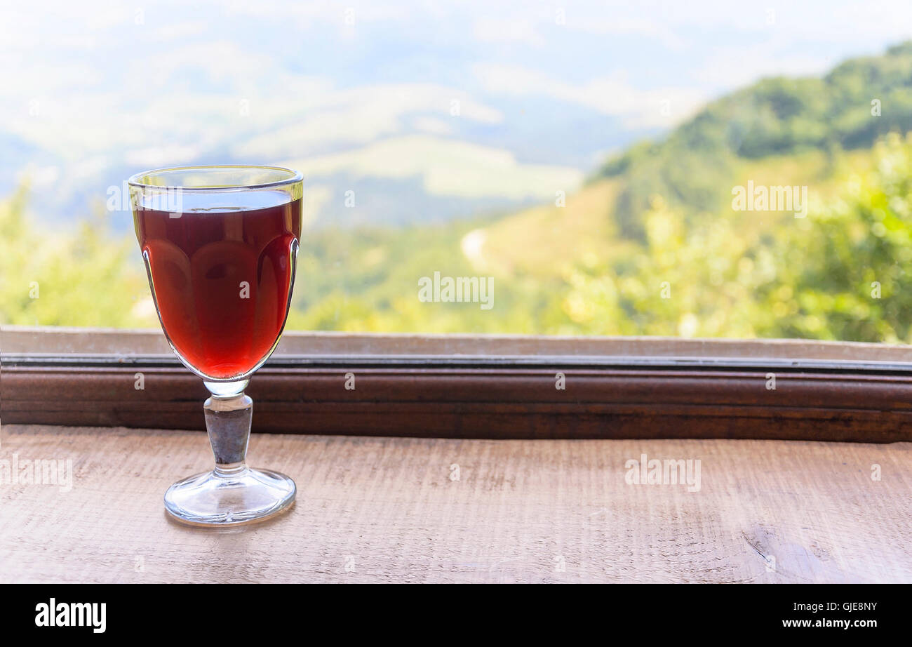 Glas Wein auf der Fensterbank mit Blick auf die Berge. Stockfoto
