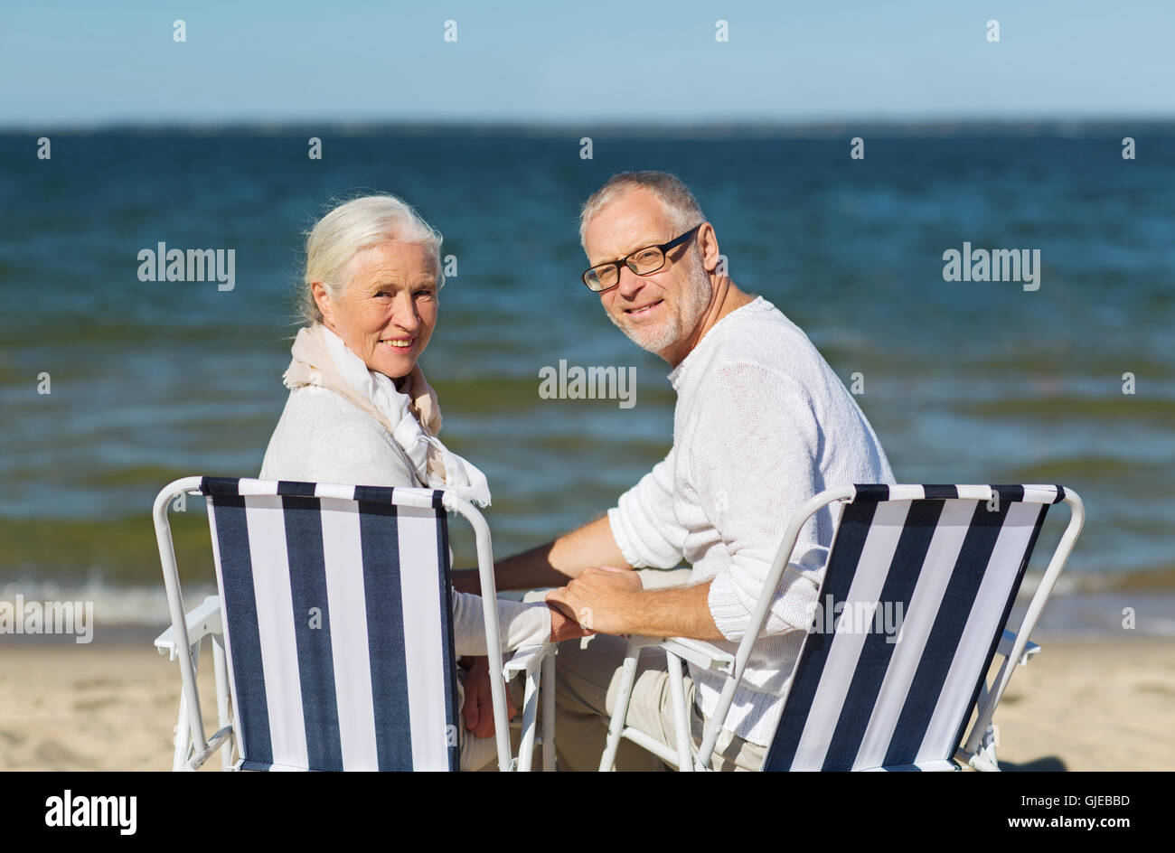 älteres paar sitzen auf Stühlen im Sommer beach Stockfoto