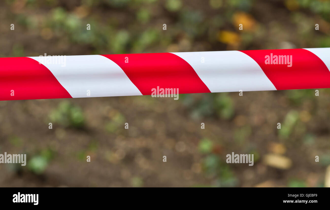 Roten und weißen Warnung Band erstreckte sich über einen unscharfen Hintergrund Stockfoto