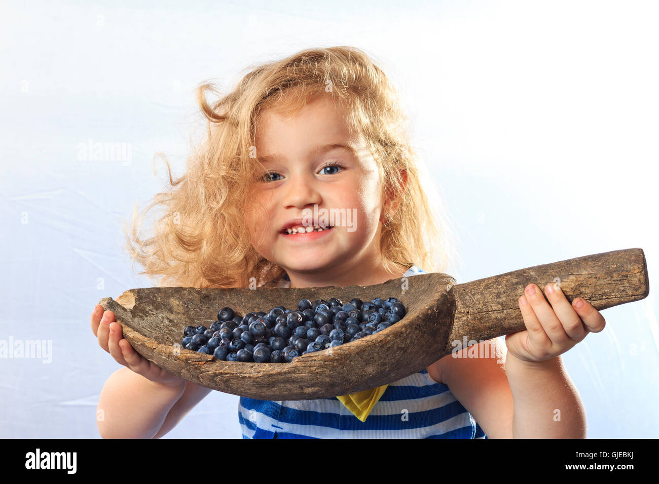 kleines Mädchen hält einen Eimer mit Beeren Blaubeeren Stockfoto