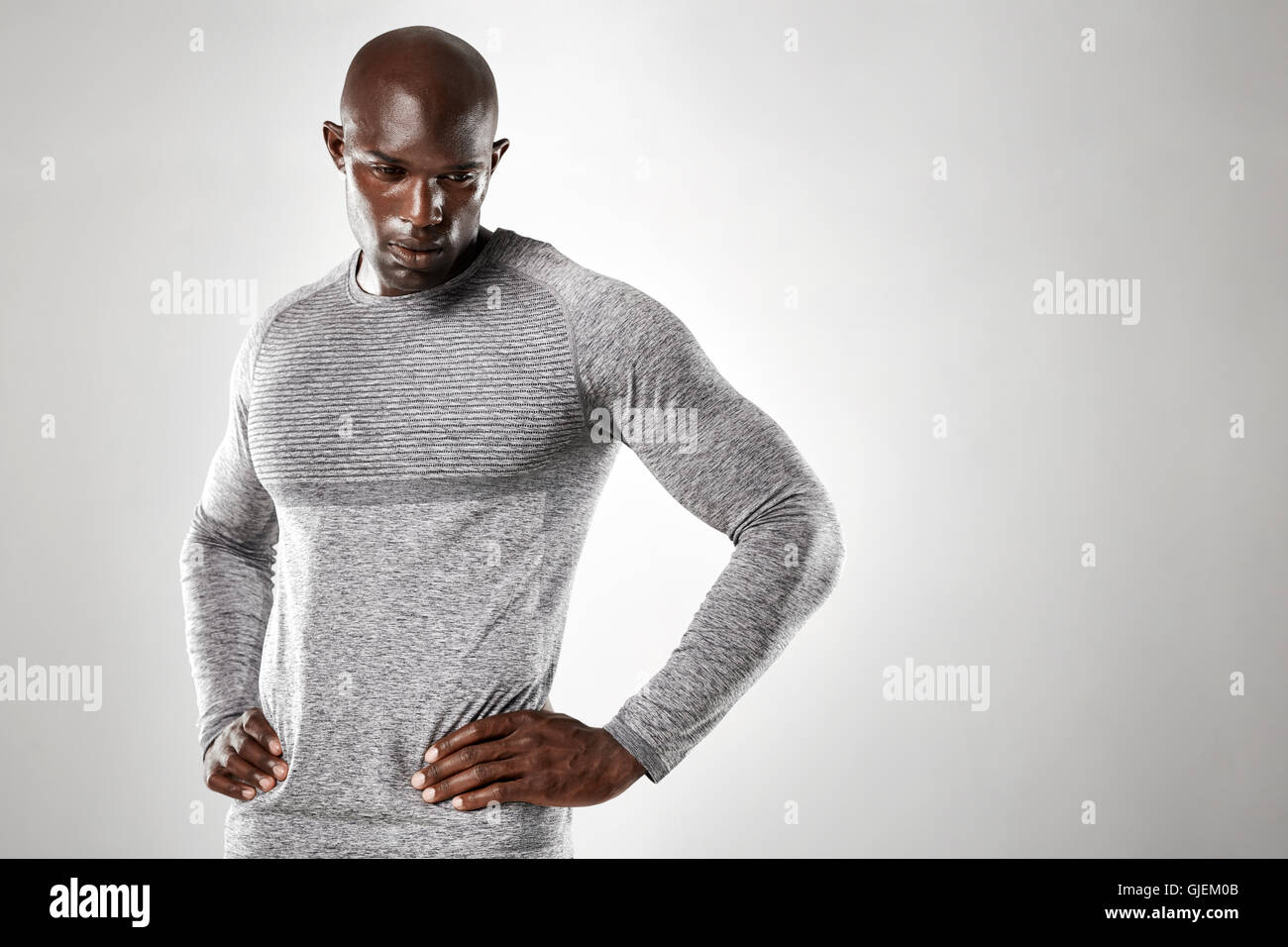 Porträt von muskulösen jungen Mann stehend mit den Händen auf den Hüften nach unten vor grauem Hintergrund. Starken afrikanischen Männermodel. Stockfoto