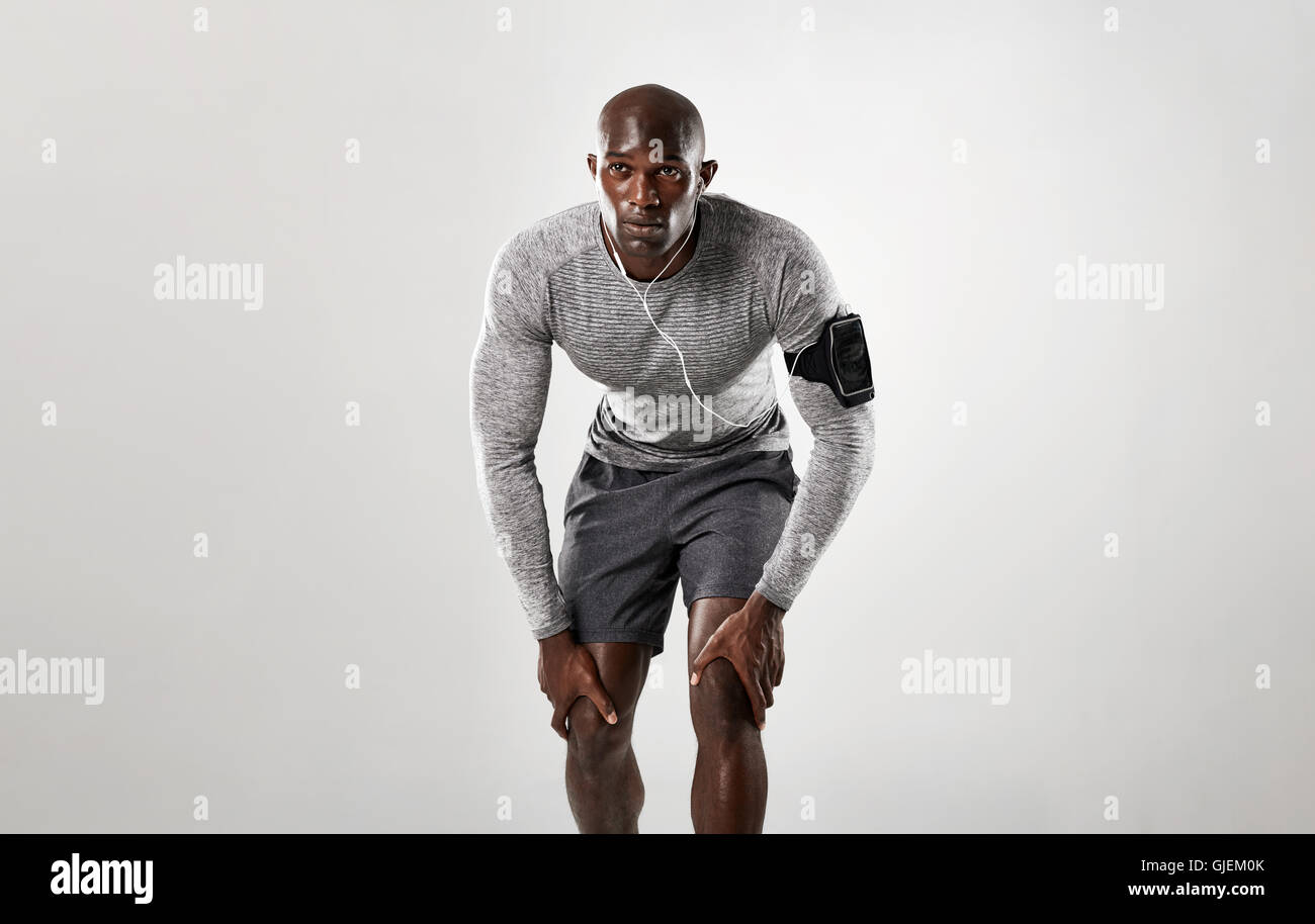 Passen Sie jungen Mann auf sein Zeichen anfangen zu laufen. Muskulösen afrikanischen Männermodel bereit für seinen Lauf über grauen Hintergrund. Stockfoto