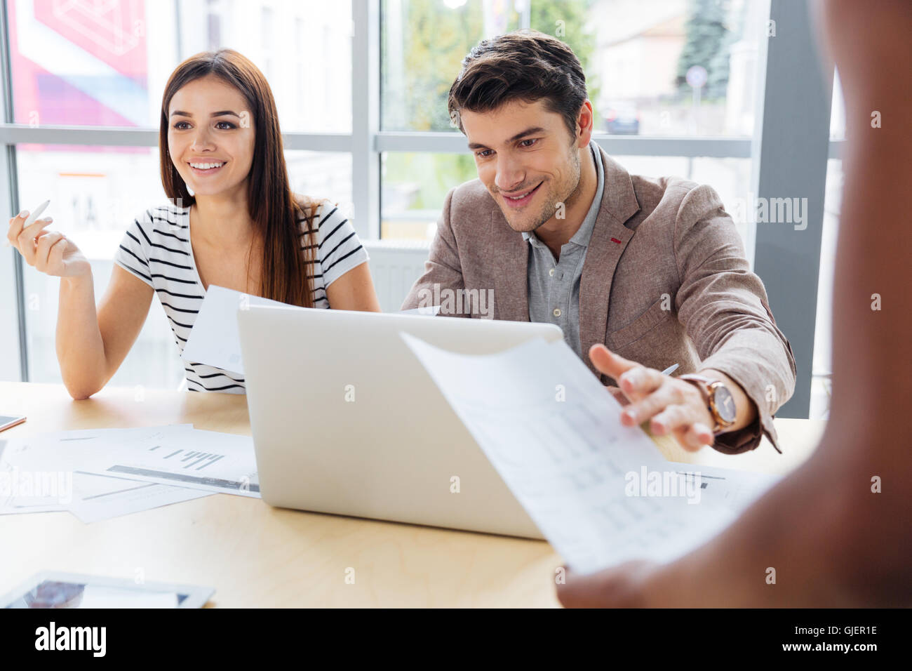 Lächelnde Frau und Mann arbeitet und Projekt diskutieren und mit Laptop im Büro Stockfoto