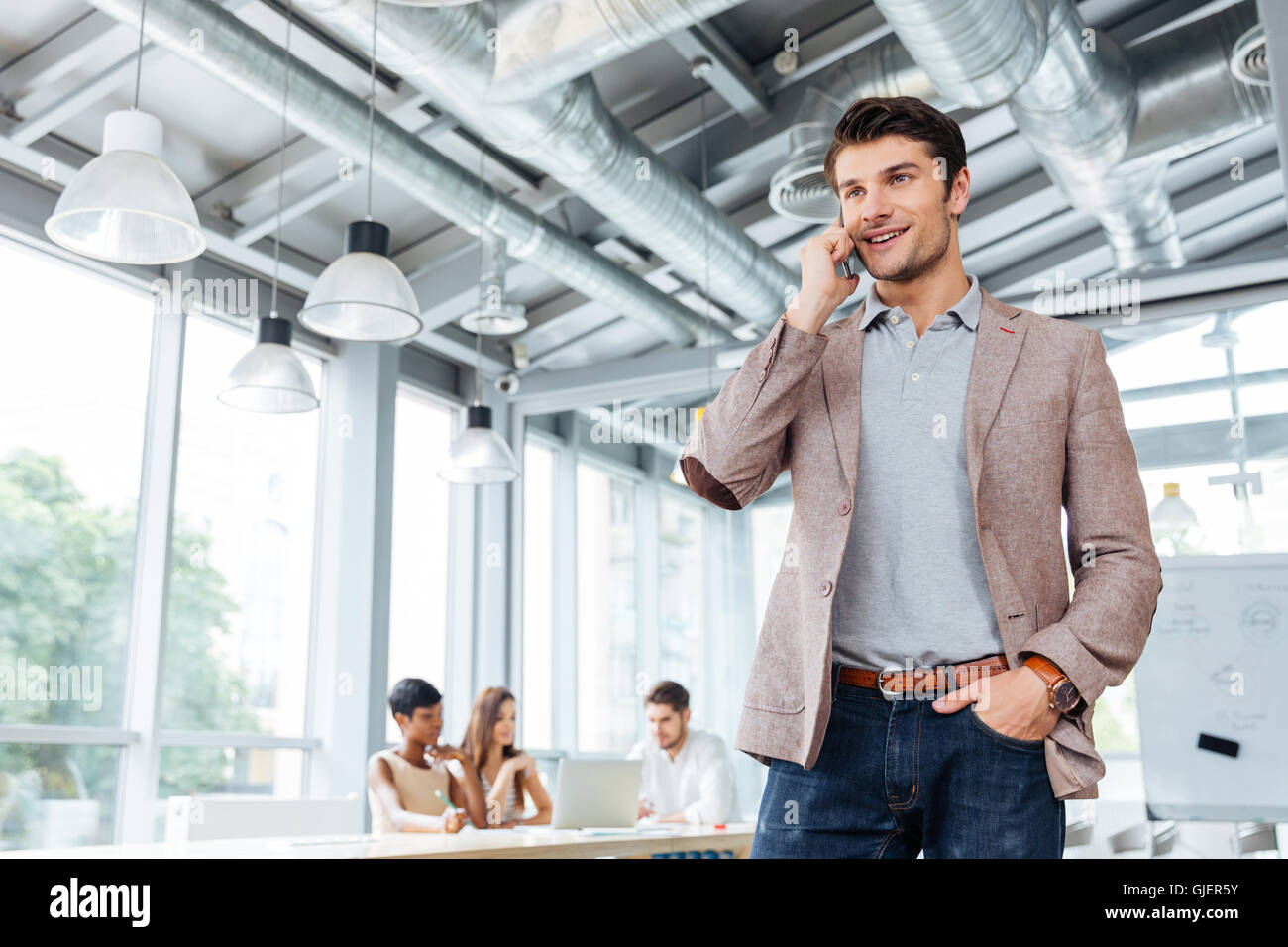 Glückliche junge Unternehmer stehen und reden über Handy im Büro Stockfoto