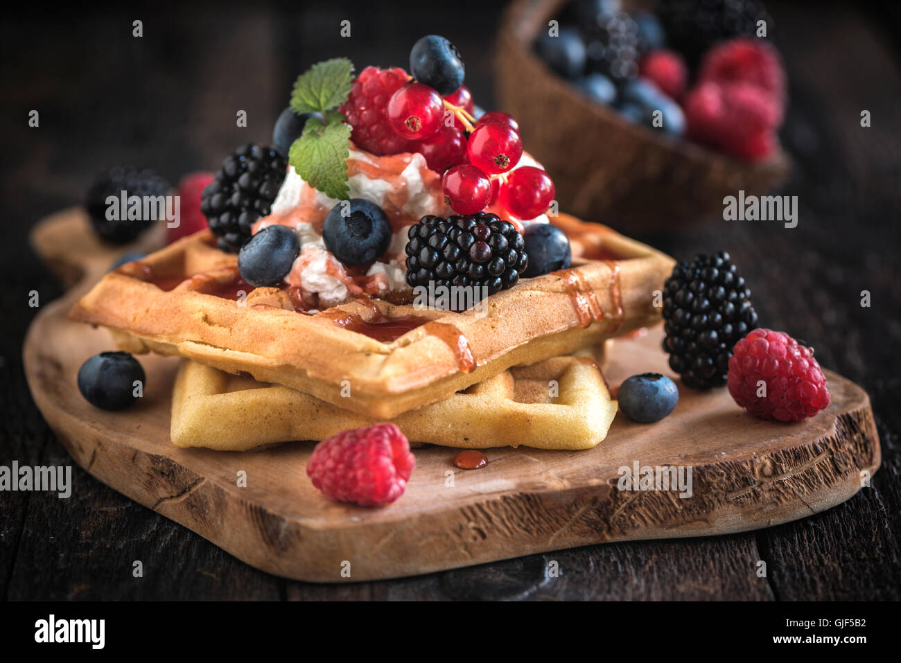 Belgien-Waffeln auf Holzbrett mit Beeren und Eis am oberen, selektiven Fokus Stockfoto