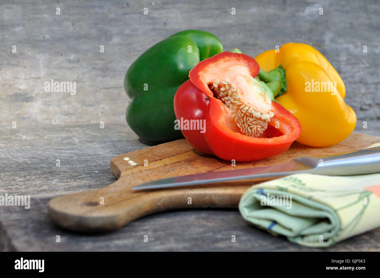 rote Paprika halbieren mit anderen an Bord mit Messer Stockfoto