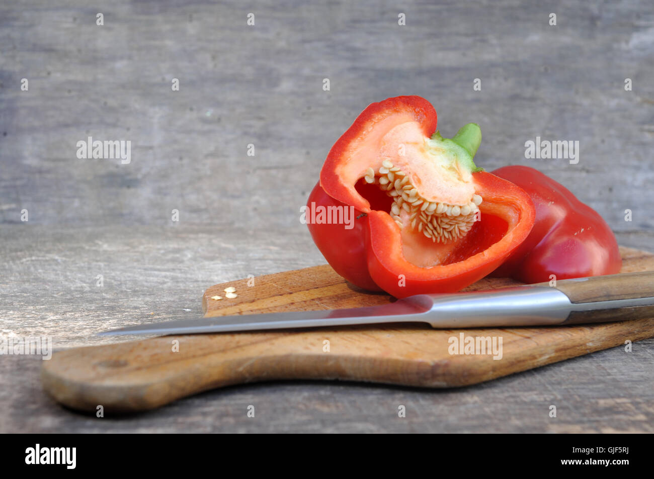 rote Paprika halbieren an Bord mit Messer Stockfoto