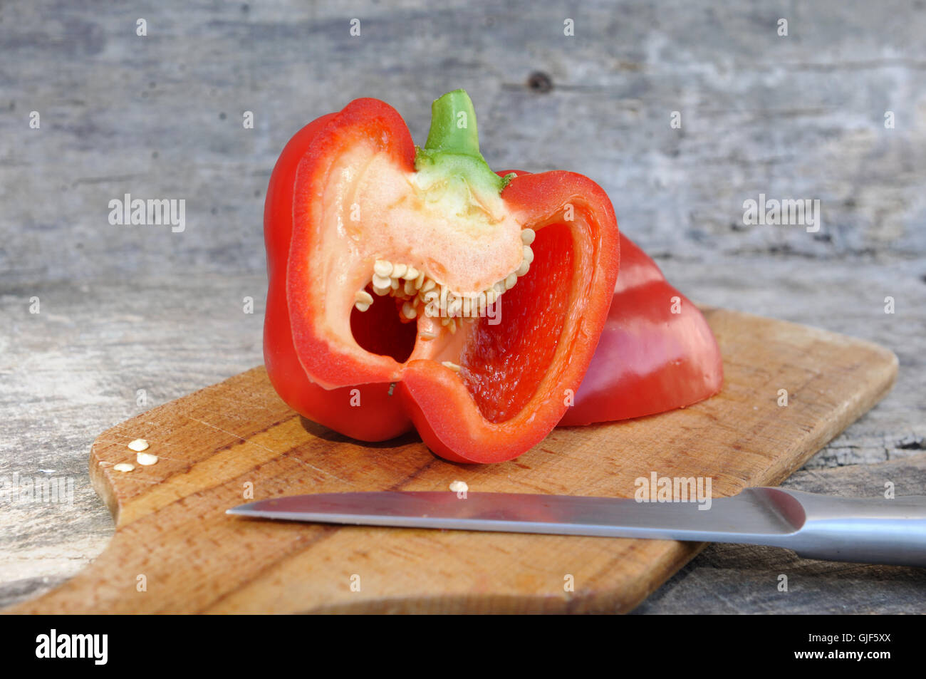 rote Paprika halbieren an Bord mit Messer Stockfoto