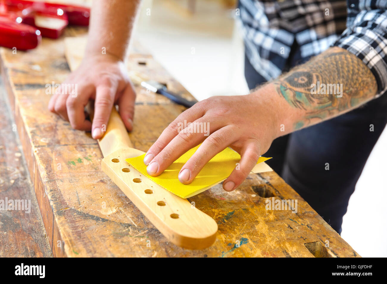 Tischler Schleifen einen Gitarrenhals aus Holz in Werkstatt Stockfoto