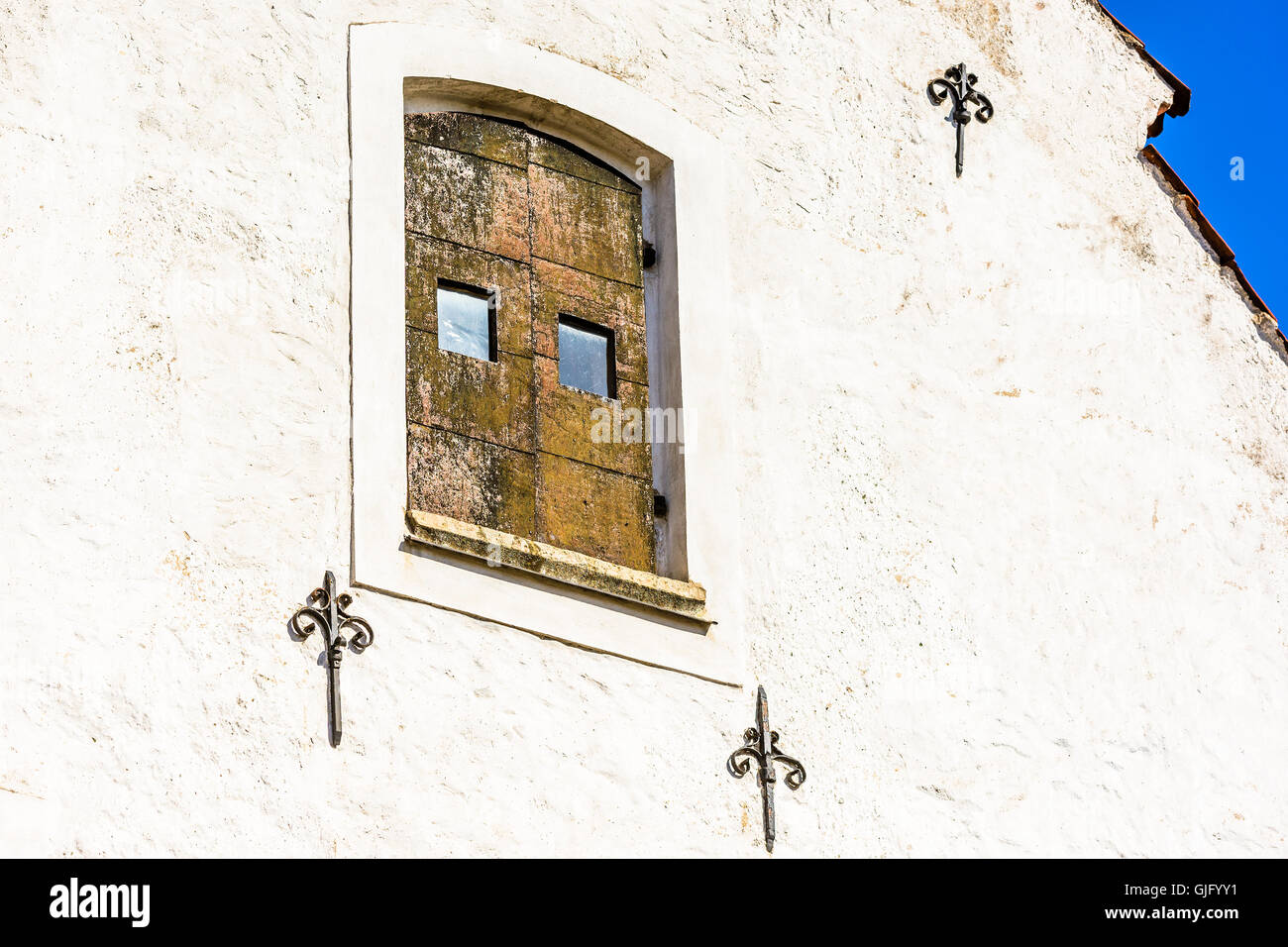 Alte Fensterläden aus Holz auf einem weißen Gebäude aus Stein. Einige Himmel sichtbar in einer Ecke. Stockfoto