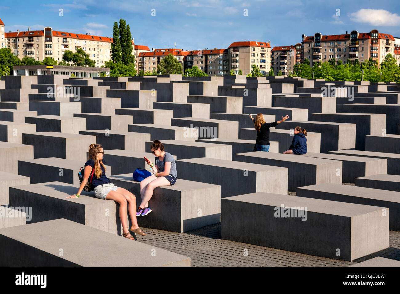 Touristen sitzen auf die Betonsteine von das Holocaust-Mahnmal für die ermordeten Juden Europas, Berlin, Deutschland. Stockfoto