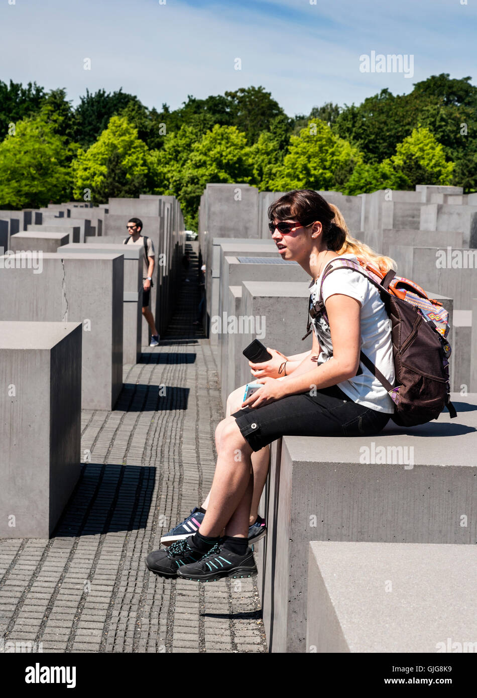 Touristen sitzen auf die Betonsteine von das Holocaust-Mahnmal für die ermordeten Juden Europas, Berlin, Deutschland. Stockfoto