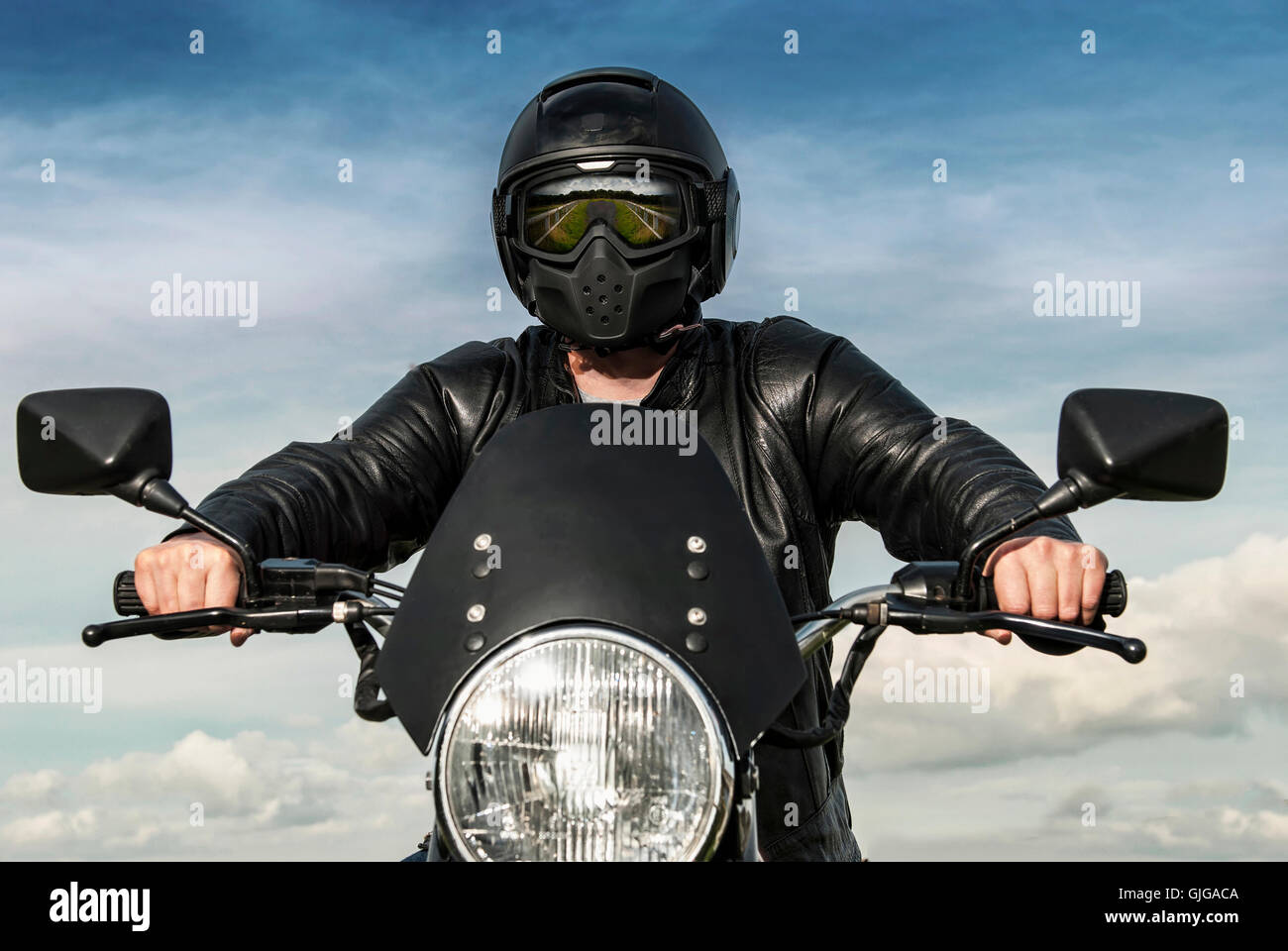 Motorradfahrer auf einem Motorrad mit schwarzen Helm Spiegelbild der Landschaft im Visier Leder Jacke blauer Himmel weiße Wolken Konzept Stockfoto