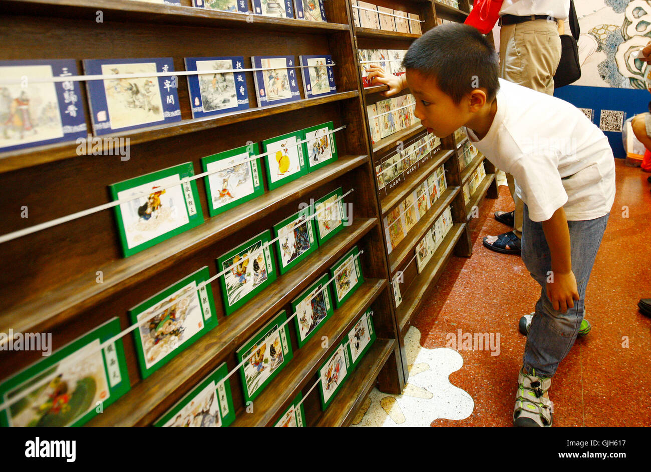 Shanghai. 17. August 2016. Ein Kind nimmt Bücher auf der 2016 Shanghai Buchmesse in Ost-China Shanghai, 17. August 2016. Kinder, die im Urlaub Tauchen in die Welt der Bücher auf der Buchmesse. © Fang Zhe/Xinhua/Alamy Live-Nachrichten Stockfoto