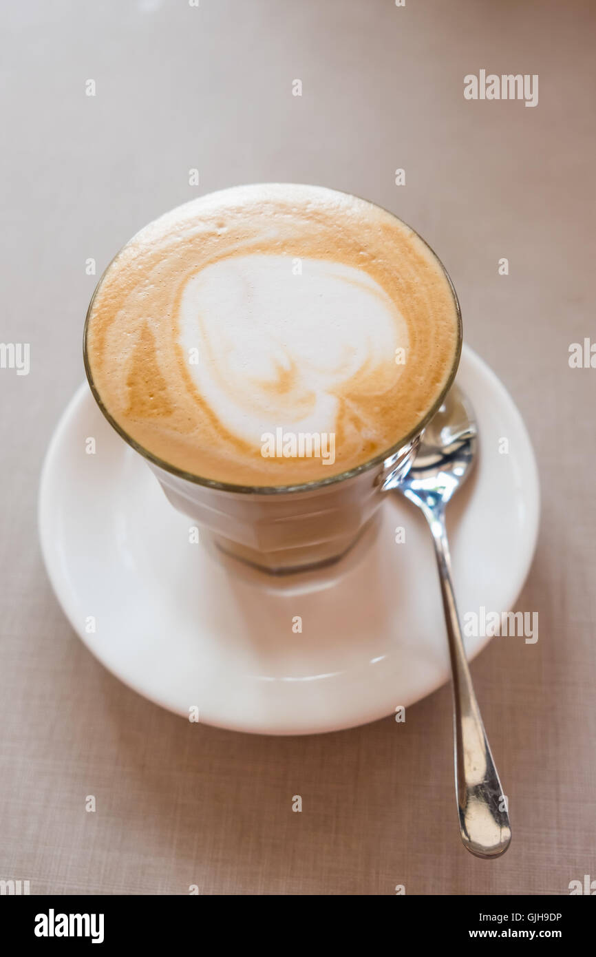 Ein Glas Kaffee mit Herzform auf Tisch im Café Latte Art. Stockfoto
