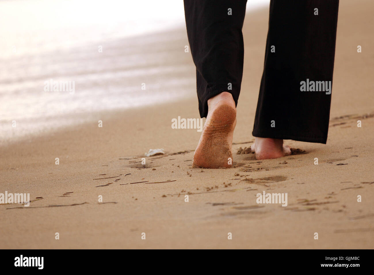 Frau geht den Strand entlang Stockfoto