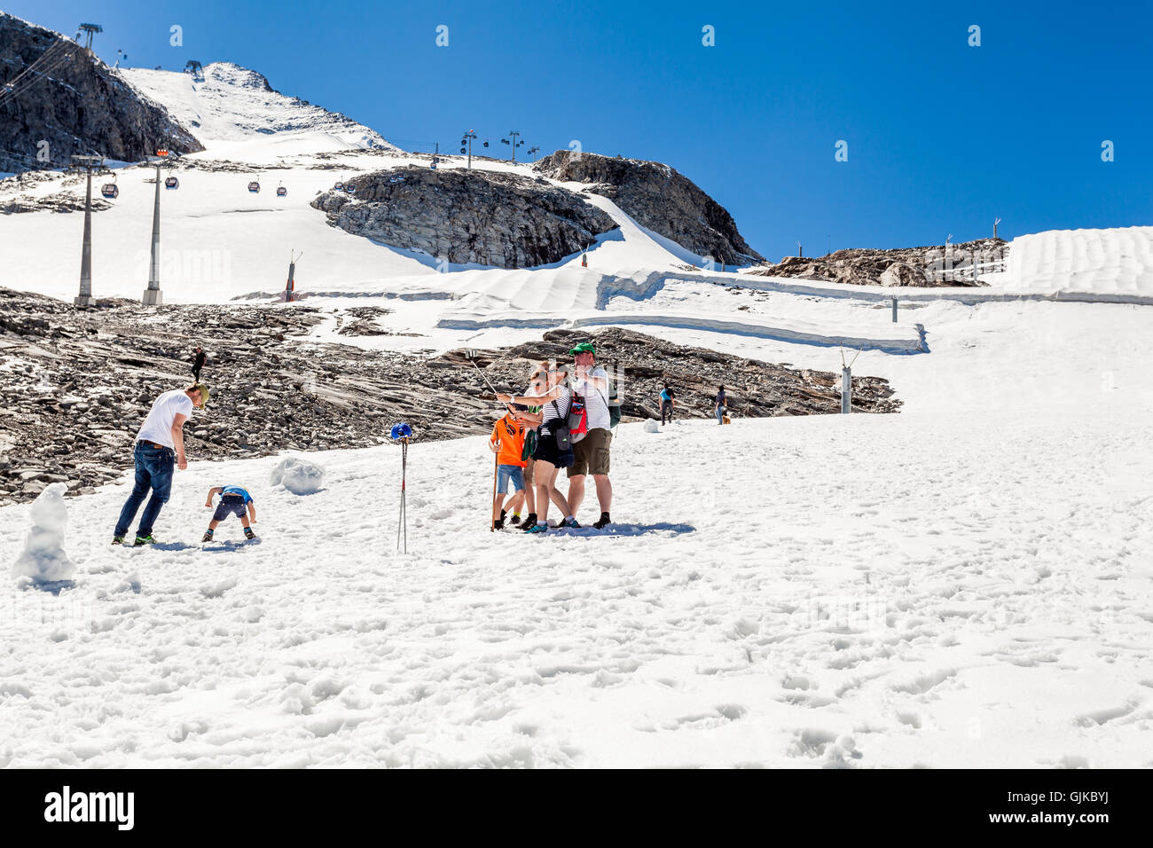 Menschen mit Spaß und ein Foto mit einem Selfie stick auf einer Loipe auf Schnee an einem sonnigen Sommertag am Hintertuxer Gletscher Stockfoto