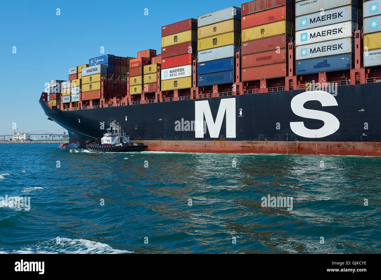 AMNAV Traktorschlepper Führung der riesigen Mediterranean Shipping Company Containerschiff, MSC Elodie, zu ihrem Liegeplatz im Hafen von Long Beach, Kalifornien, USA. Stockfoto