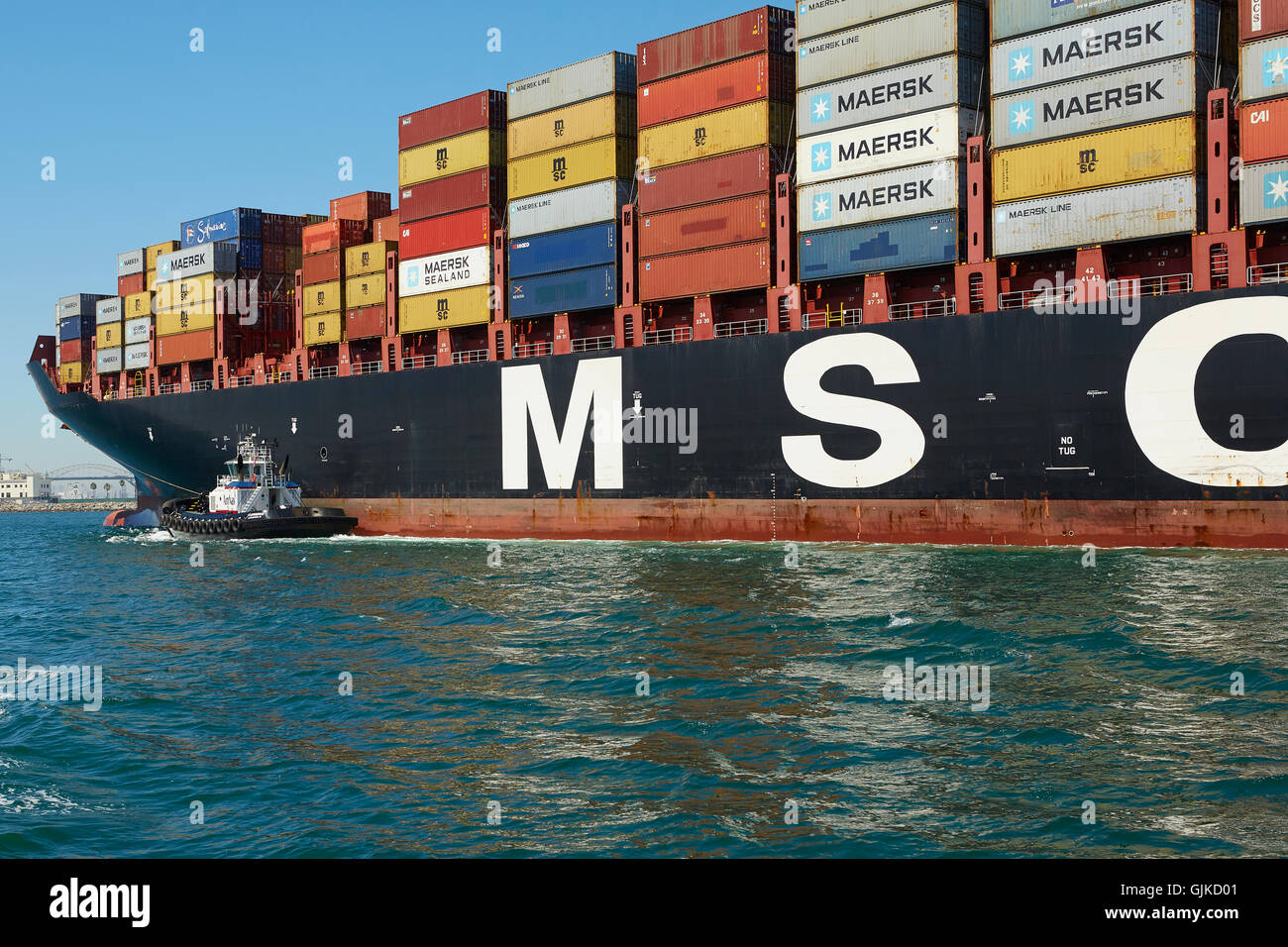 AMNAV Traktorschlepper Führung der riesigen Mediterranean Shipping Company Containerschiff, MSC Elodie zu Ihrem Liegeplatz im Hafen von Long Beach, Kalifornien, USA. Stockfoto