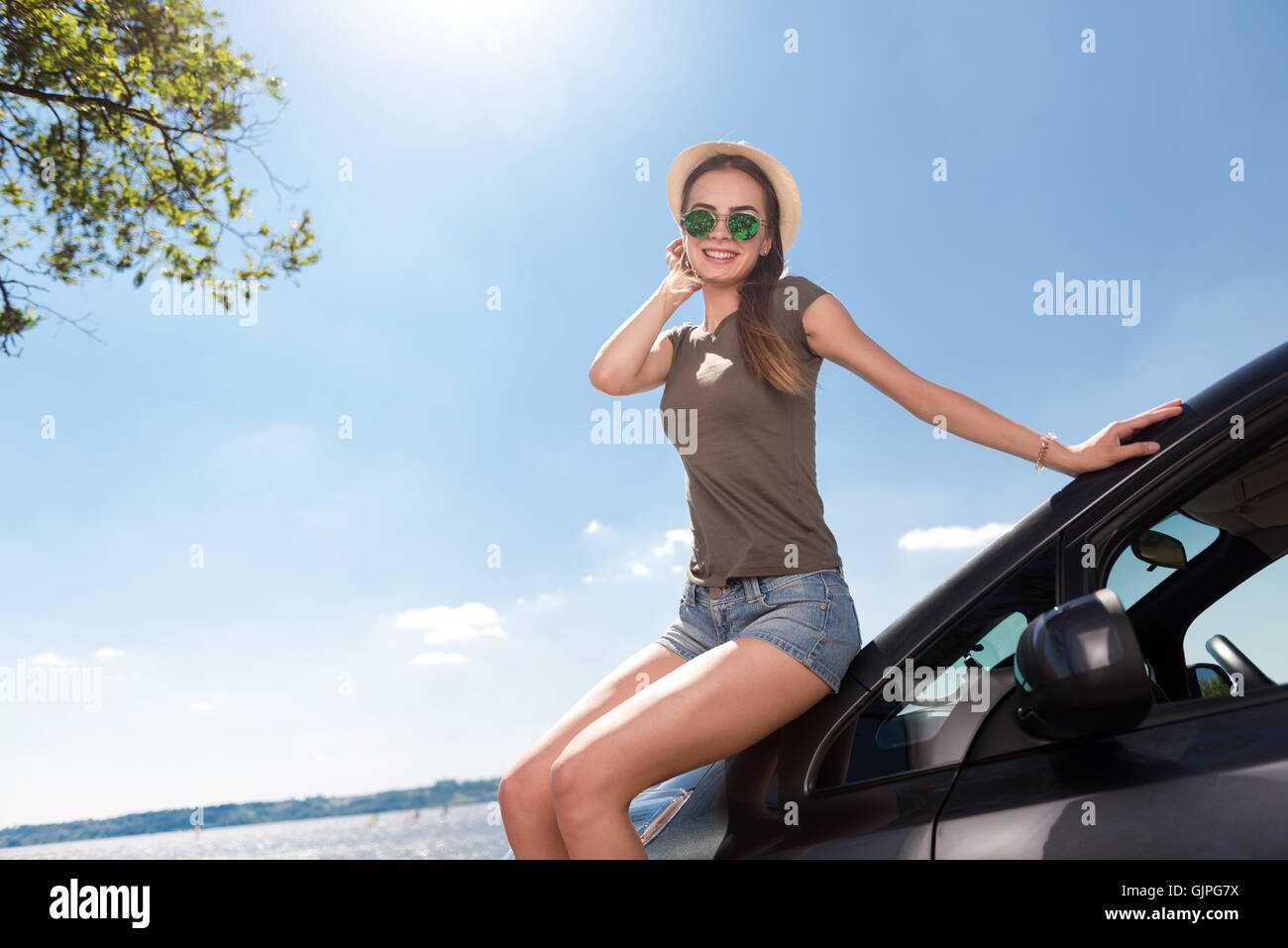 Fröhliche Frau, stützte sich auf das Auto Stockfoto