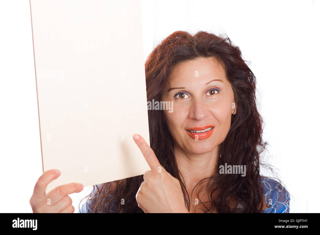 Glücklich Reife Frau mit arabischen und nahöstlichen somatische Merkmale, gefärbt mit Henna Haare Lächeln und Falten und im Alter von Haut mit ihrem Finger auf leeren weißen Schild sie im Hochformat hält Stockfoto