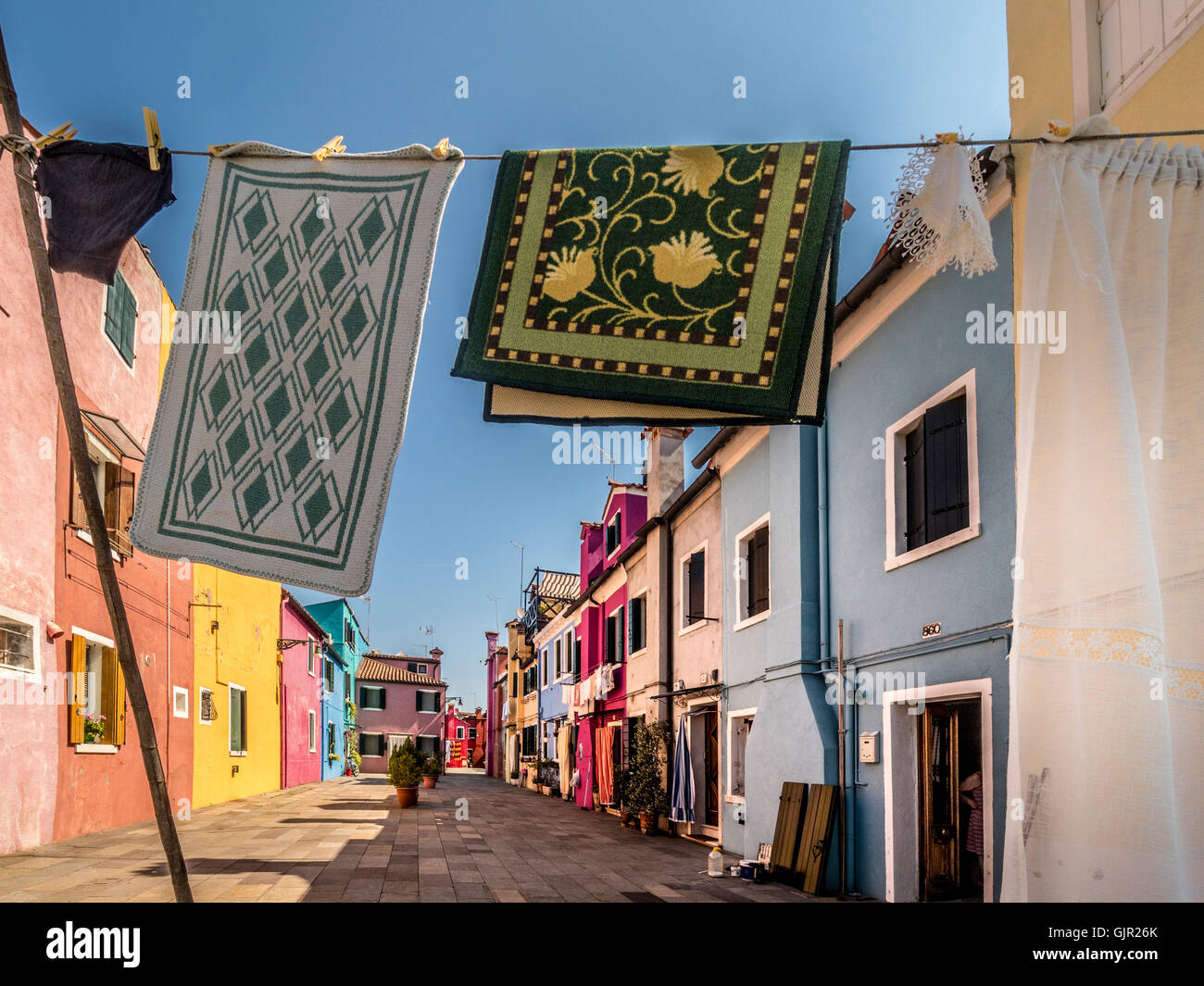 Das traditionelle bunt bemalte Reihenhaus mit Waschküche, die draußen an Wäscheleinen hängt, auf der Insel Burano. Italien. Stockfoto