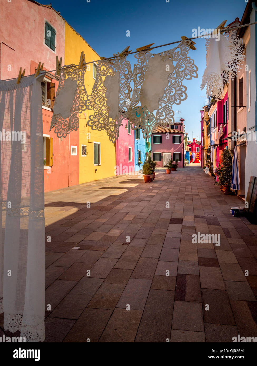 Wäscheleine mit Wäscheleine, die auf ihr gekoppelt ist, trocknet in den Hinterhöfen der traditionellen bunt bemalten Terrassenhäuser der Insel Burano. Venedig, Italien. Stockfoto