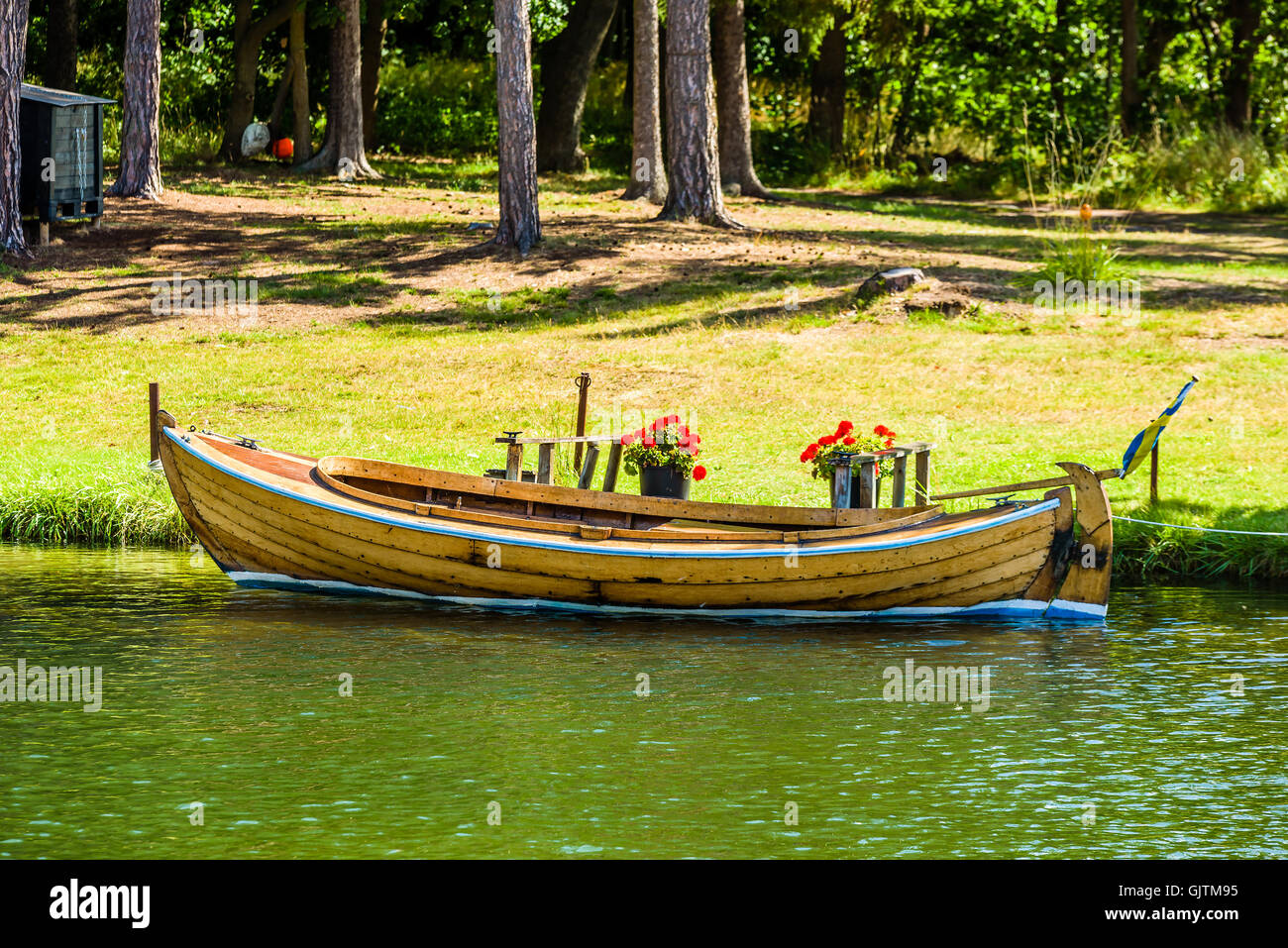 Alten Holzmotorboot vertäut am Ufer mit Kiefern und Gräsern im Hintergrund. Stockfoto