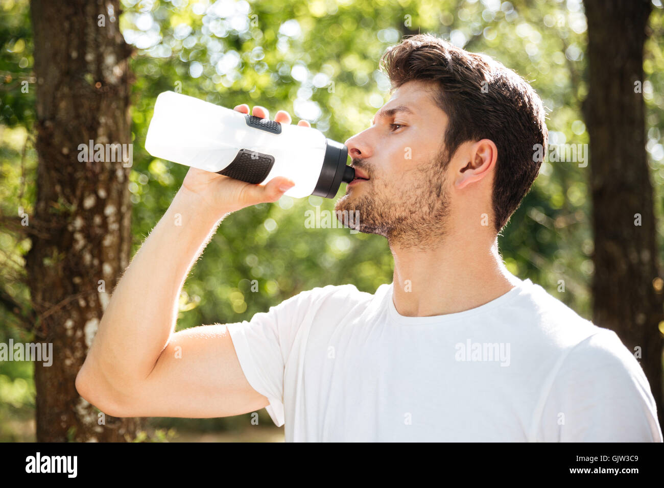 Nahaufnahme von gut aussehenden jungen Mann Athlet Trinkwasser im Wald Stockfoto