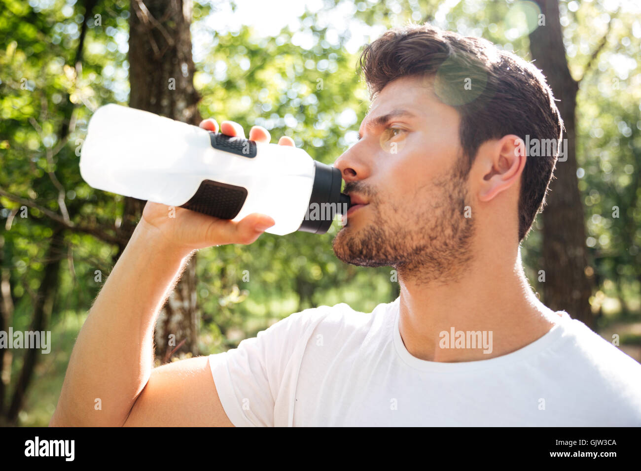Porträt von attraktiven jungen Sportler stehen und Trinkwasser im freien Stockfoto