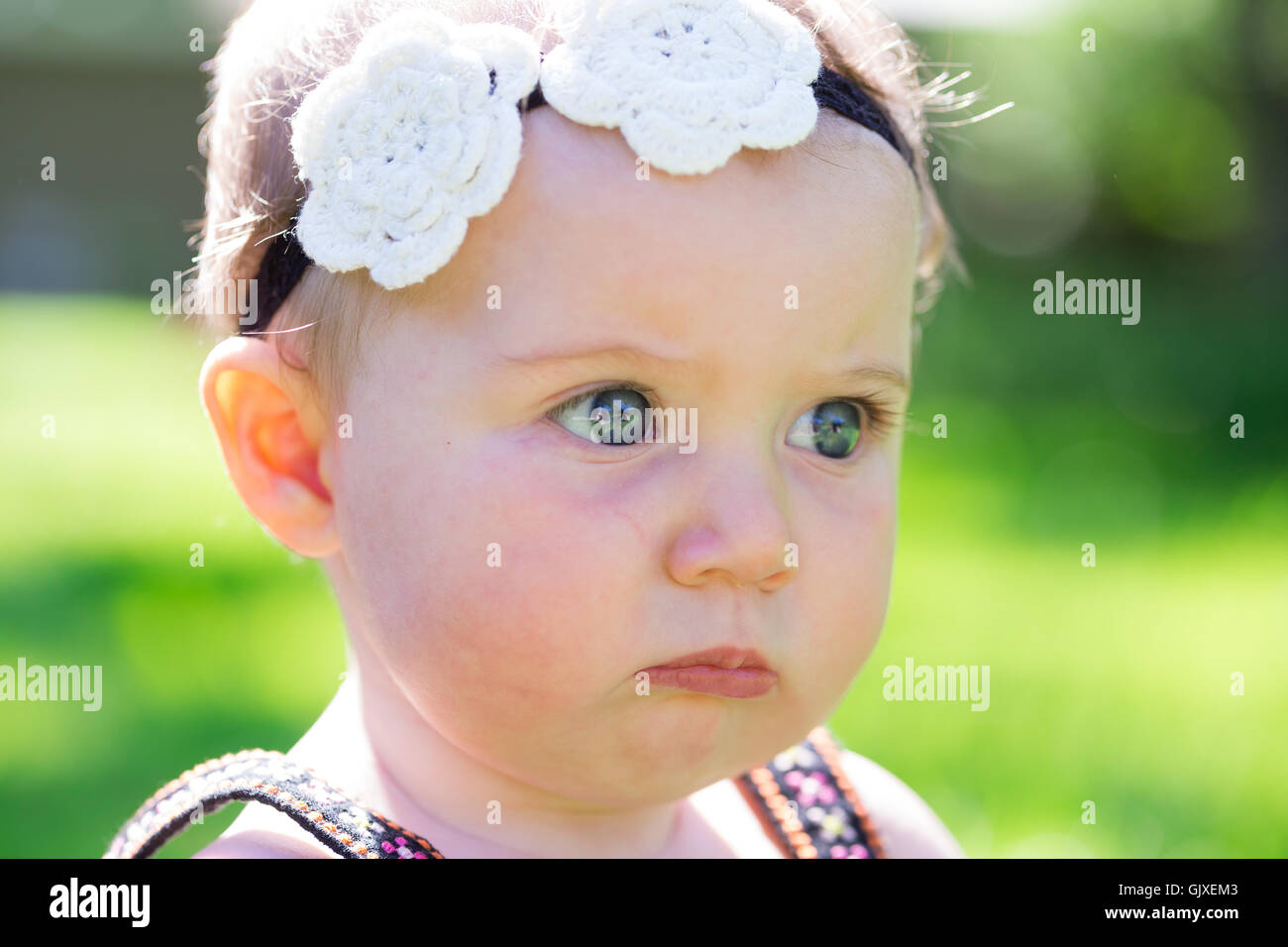 Babymädchen an etwa 6 Monate alt im Freien in einer natürlichen Umgebung mit vorhandenem Licht für ein Lifestyle-Porträt. Stockfoto