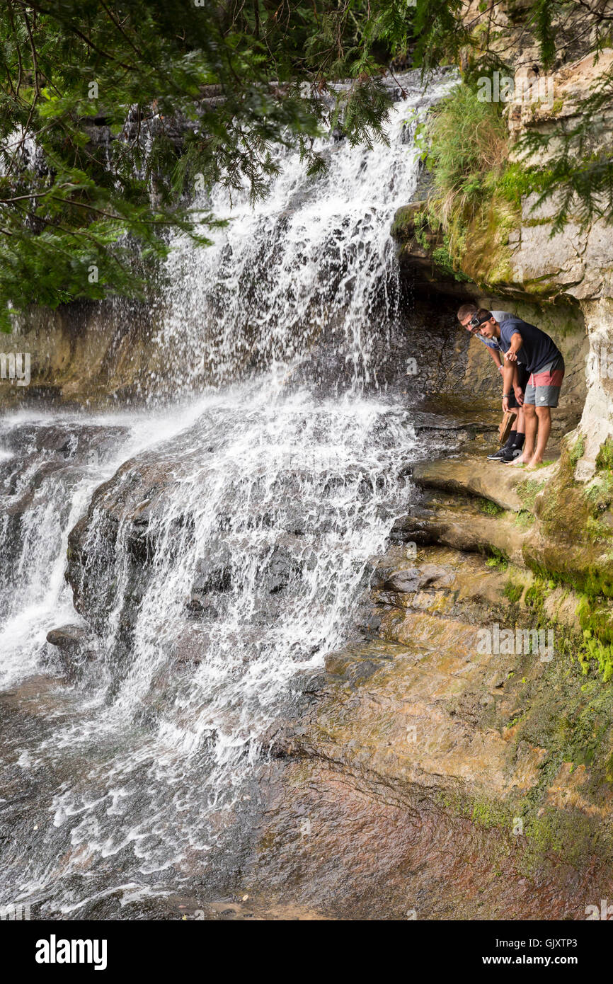 Sundell, Michigan - Touristen Aufstieg hinter Laughing Whitefish Falls, die 100 Fuß über ein Kalkstein Escarpment Tropfen. Stockfoto