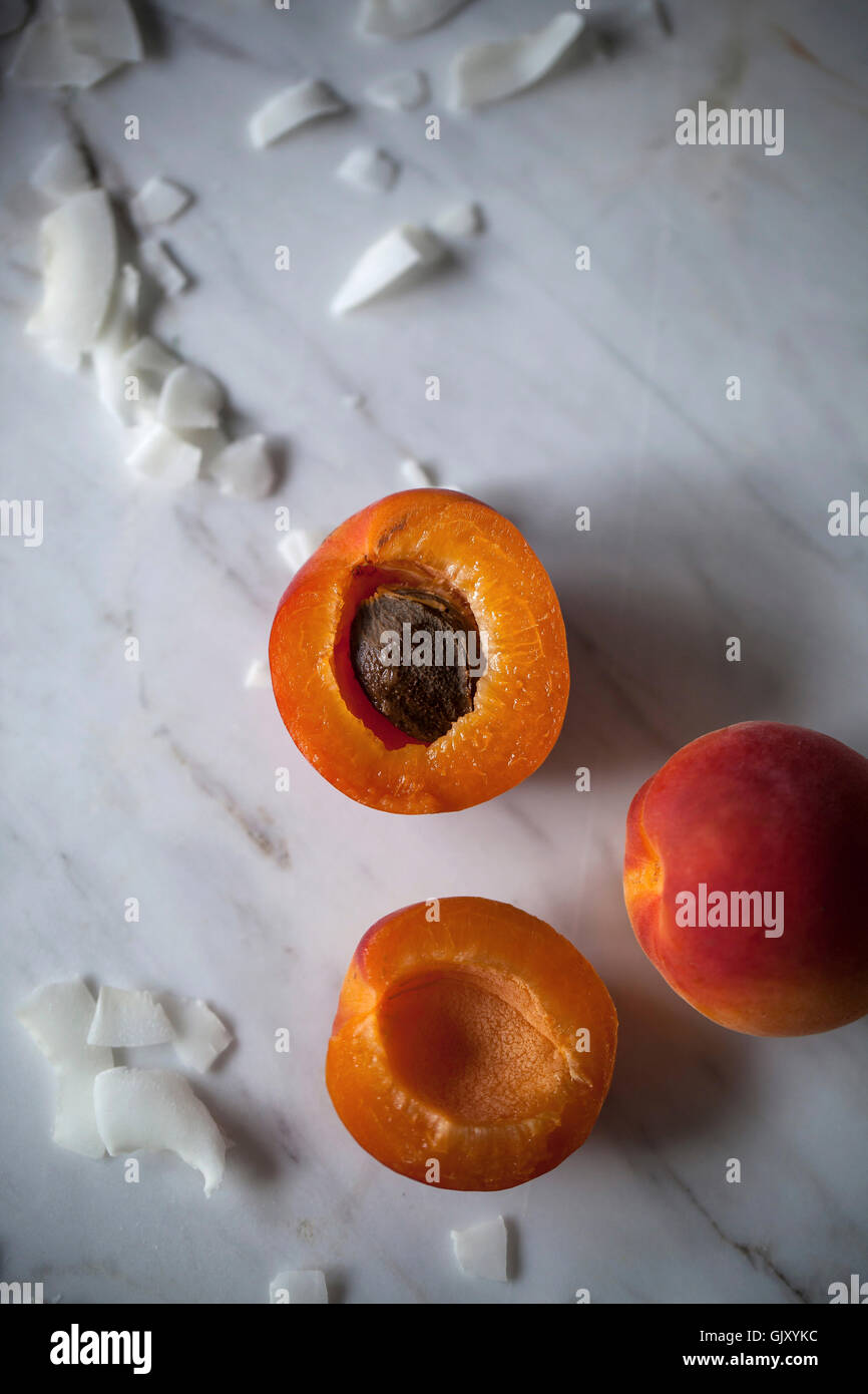 Frische Aprikosen und Kokosflocken auf weißen Marmor Tisch Stockfoto