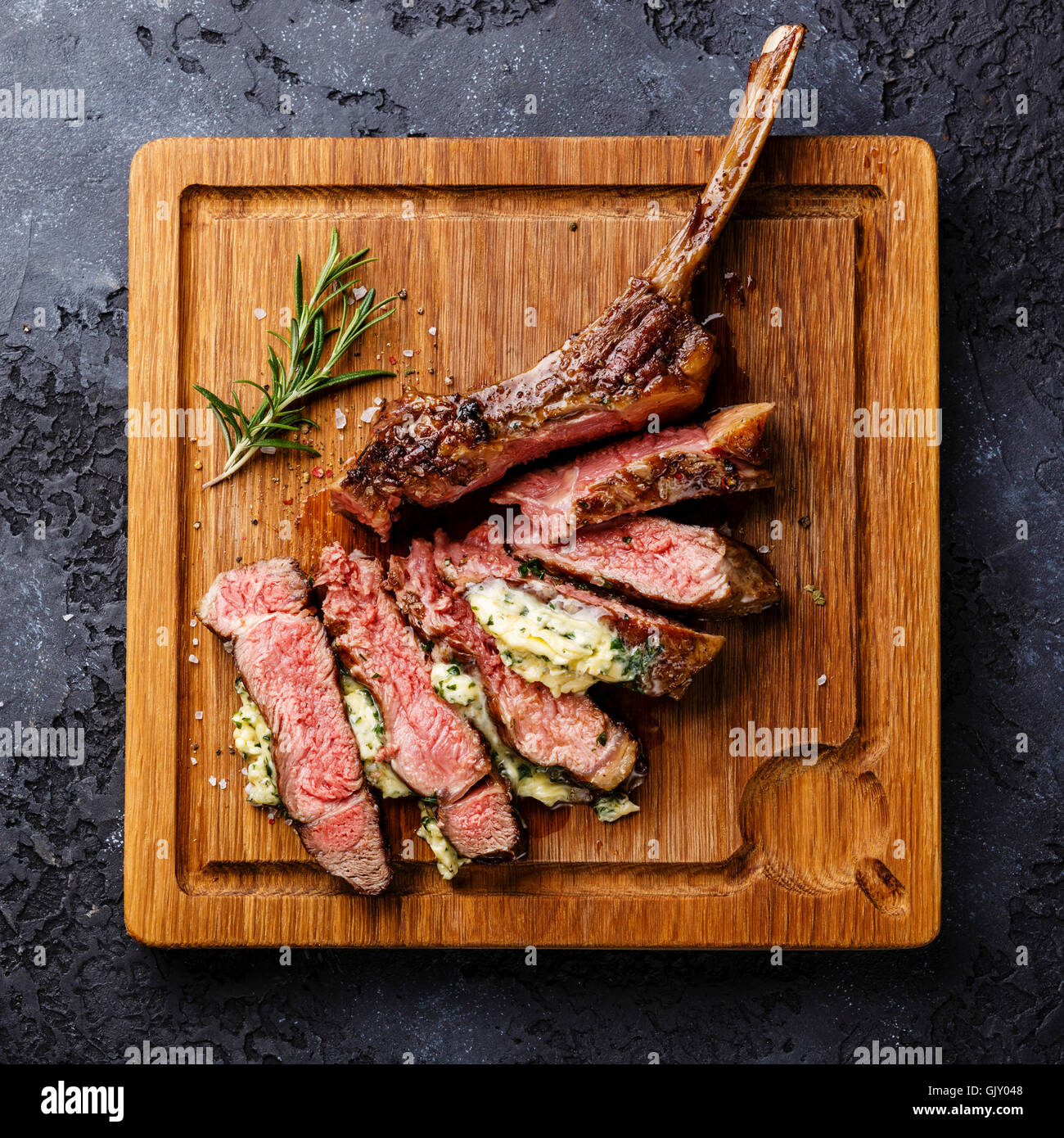 In Scheiben geschnitten gegrillt Medium selten Grill Steak auf Knochen Kalbfleisch Rippe mit Kräuterbutter auf dunklem Hintergrund Stockfoto